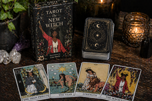 Tarot cards and book titled 'The New Witch' on a wooden surface with candles and crystals.